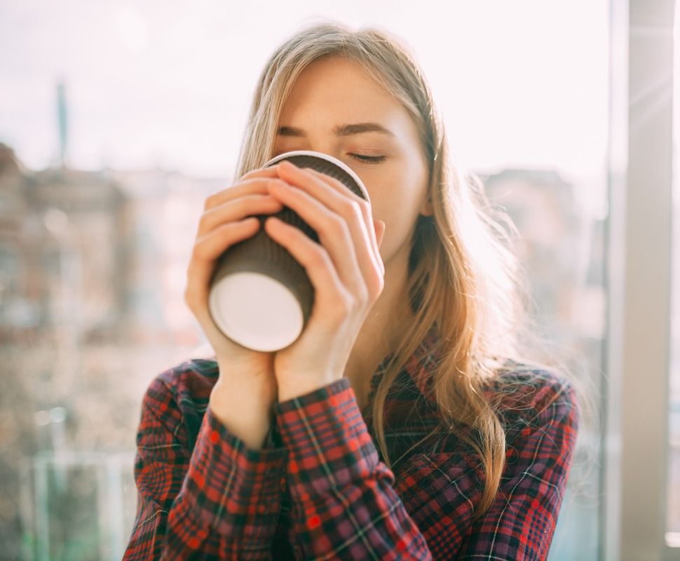 mujer toma cafe con ojos cerrados